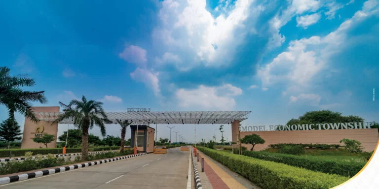 Ground-level MET City entrance gate with landscaping and palm trees